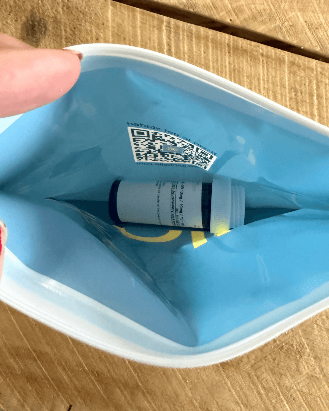 Inside the blue Belle branded resealable pouch: a QR code sticker and the white prescription bottle holding the tirzepatide vial