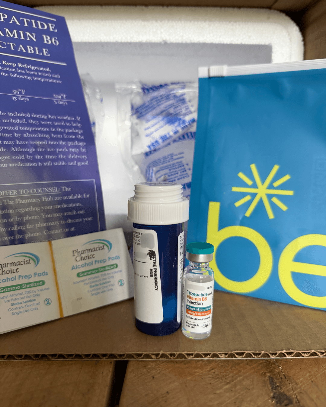 Belle tirzepatide unboxing: 4 mL vial, Pharmacy Hub prescription bottle, storage card, alcohol prep pads, and blue Belle pouch in the cooler