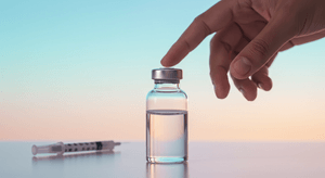 hand points to a medication vial compounding