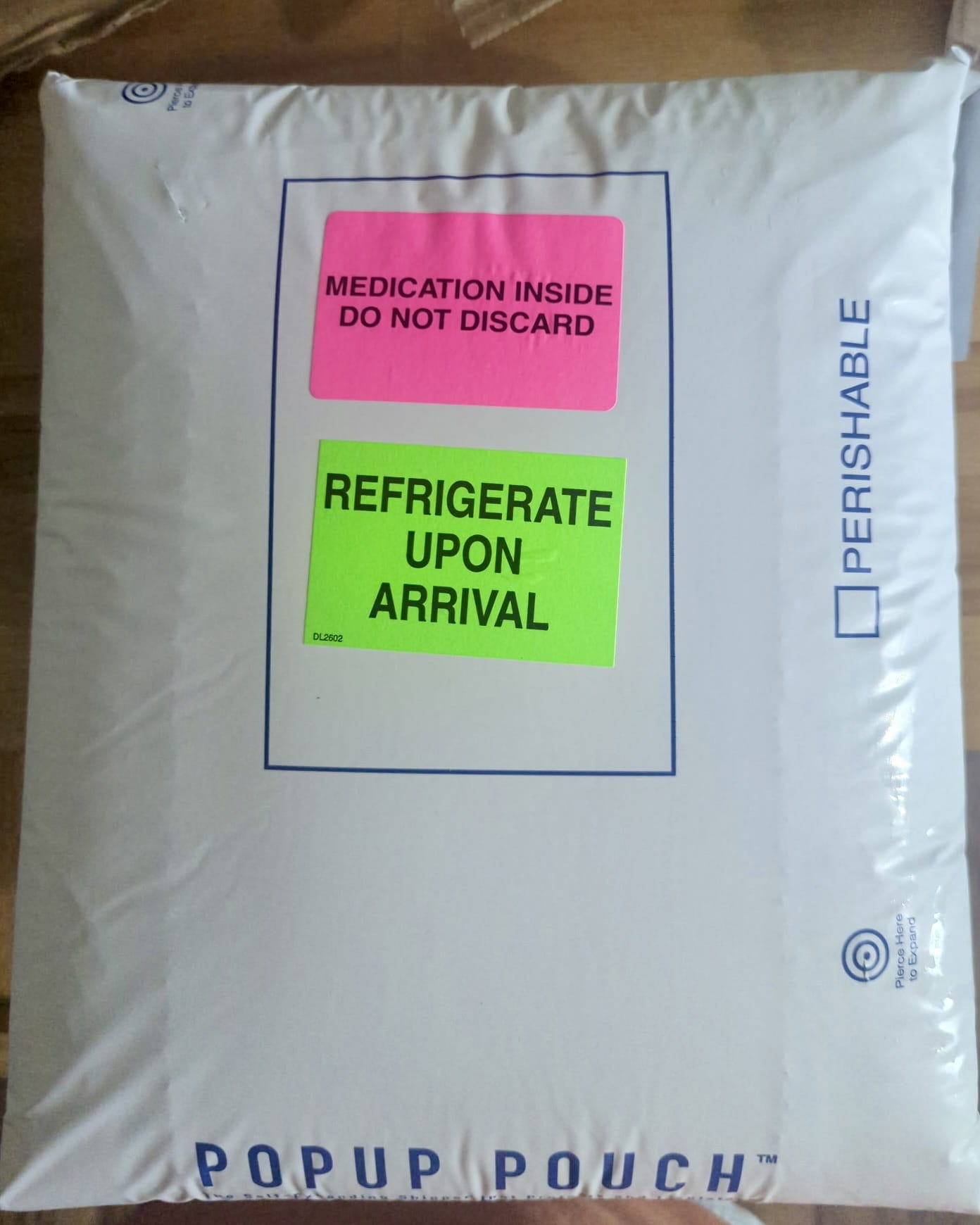 Insulated Popup Pouch mailer from the Ivim Health shipment with pink Medication Inside Do Not Discard and green Refrigerate Upon Arrival stickers