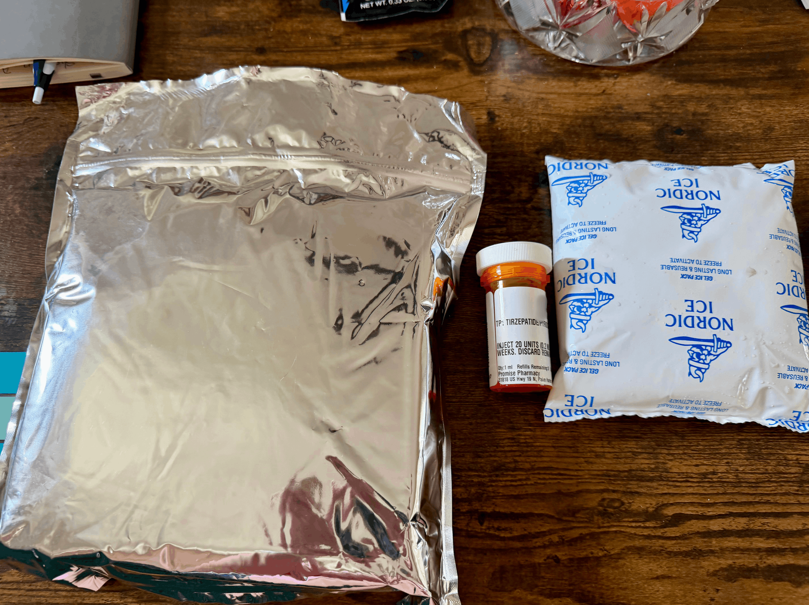 Promise Pharmacy mylar pouch with the pharmacy bottle and Nordic Ice gel pack laid out on a table