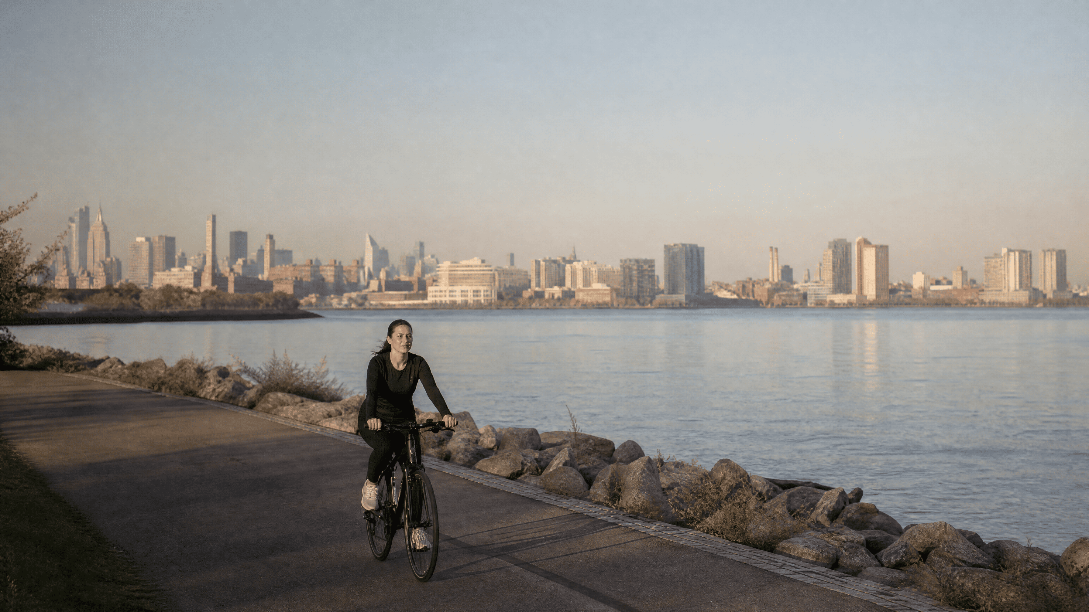 woman in her 30s riding a bicycle on a riverfront path