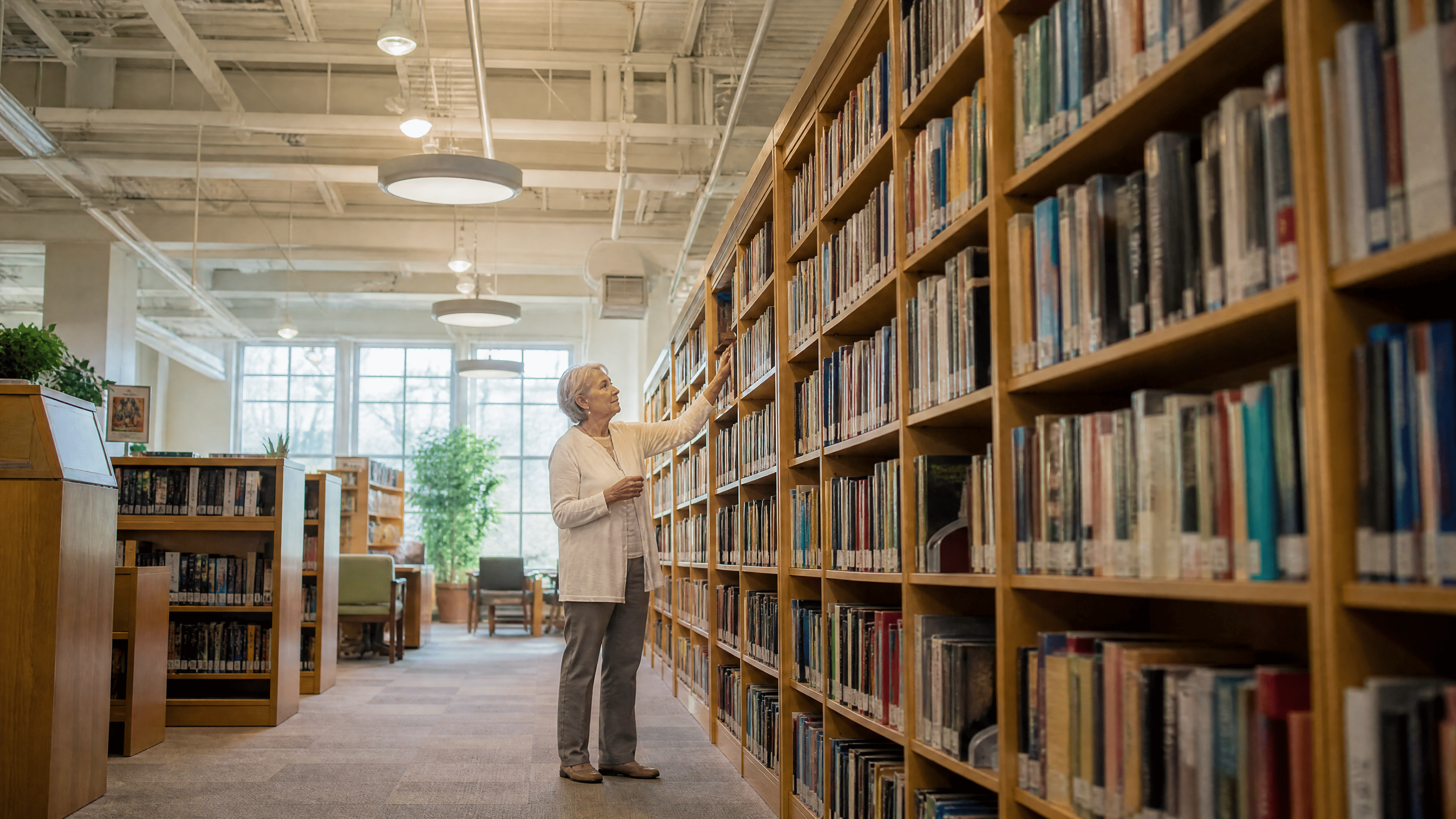 woman in her 60s reaching for a book in the library