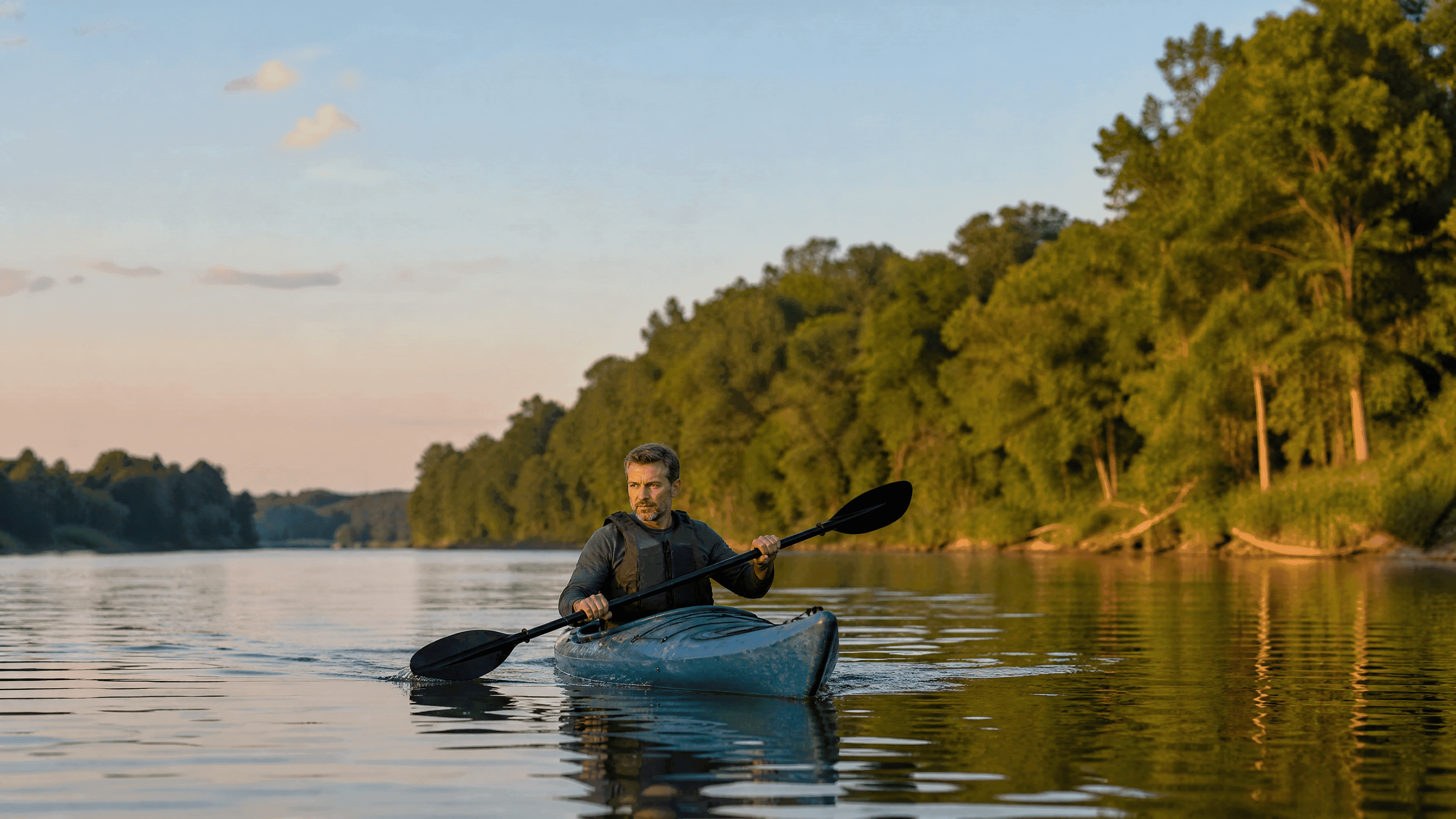 A man in his 40s kayaks on a still river