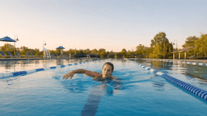 A white woman in her 40s swimming laps in an outdoor community pool