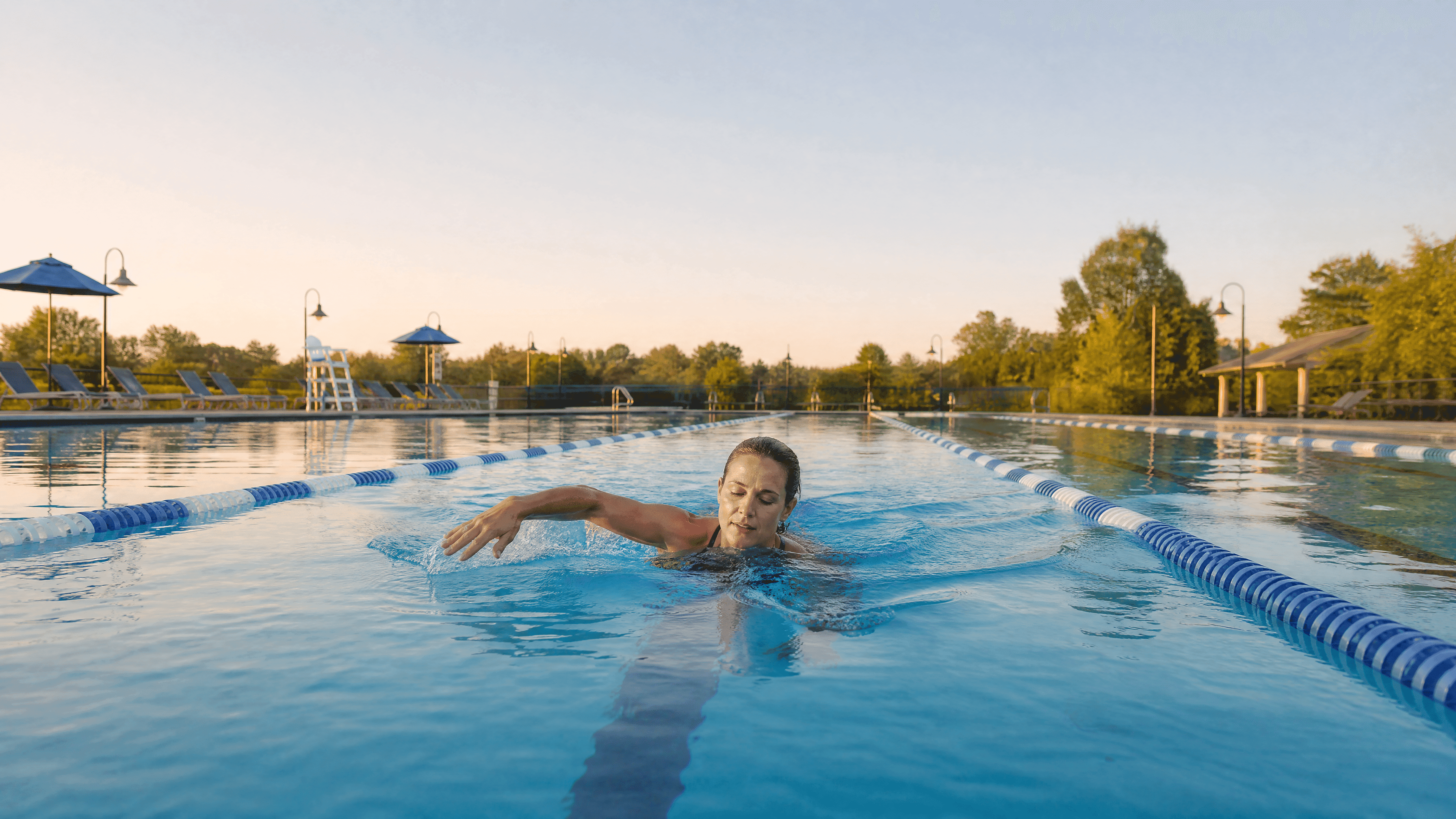 A white woman in her 40s swimming laps in an outdoor community pool