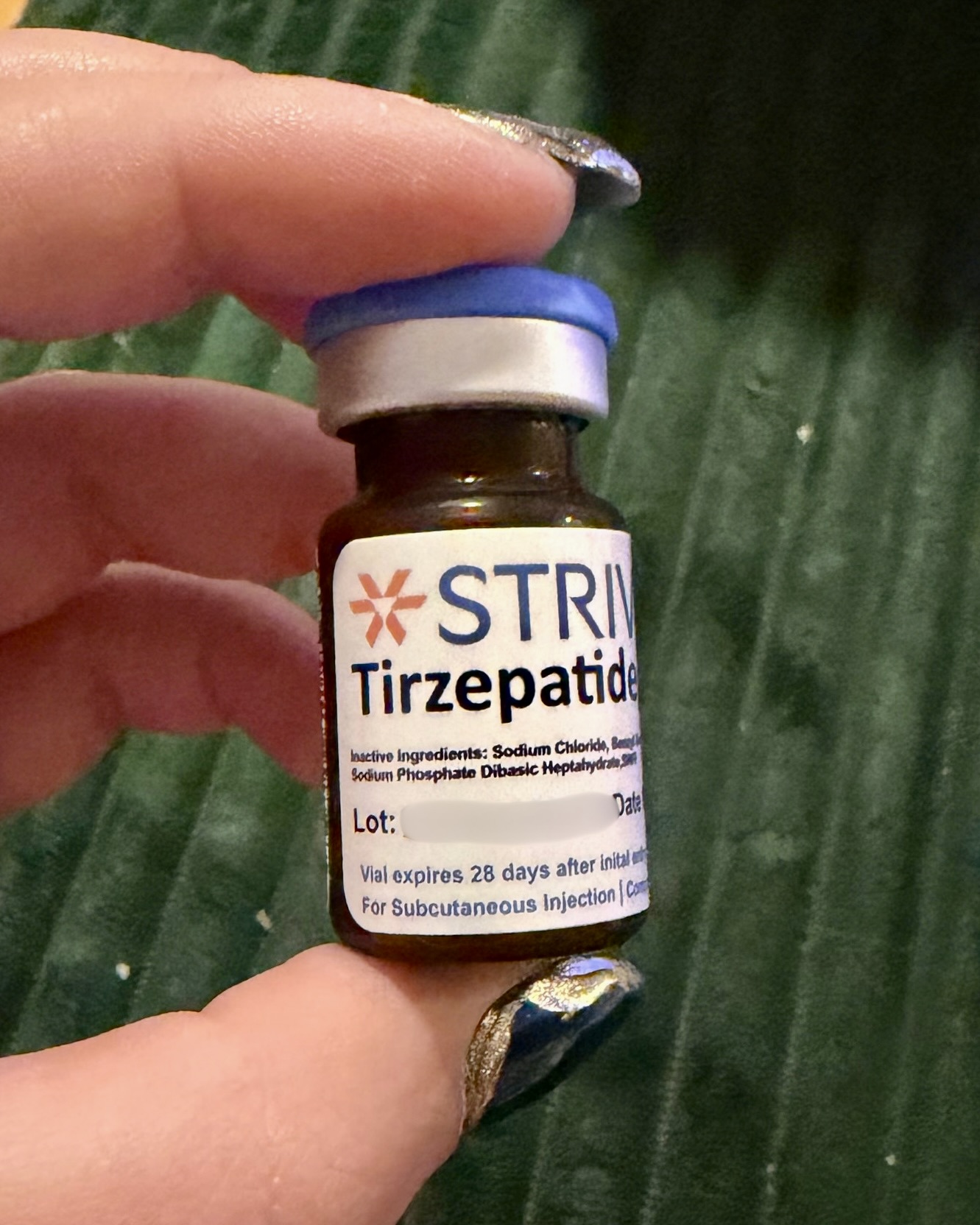 Amber Strive Tirzepatide vial with blue flip cap held in hand, showing inactive ingredients and vial expires 28 days after initial entry
