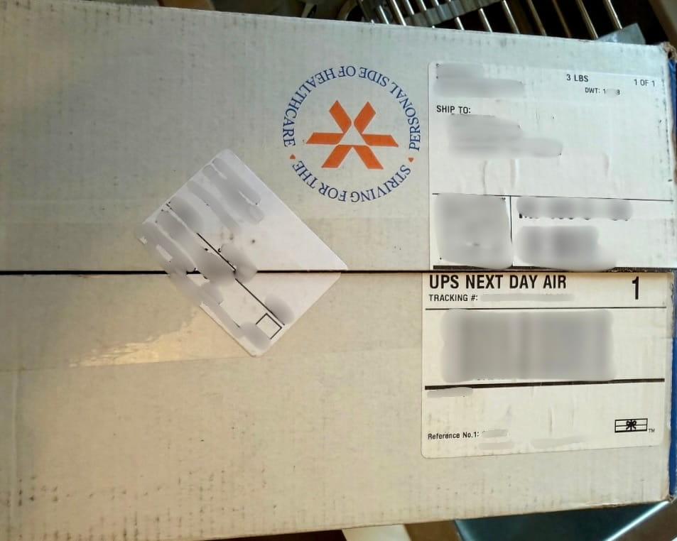 Strive Pharmacy shipping box top with a UPS Next Day Air label and a circular stamp reading striving for the personal side of healthcare, labels masked