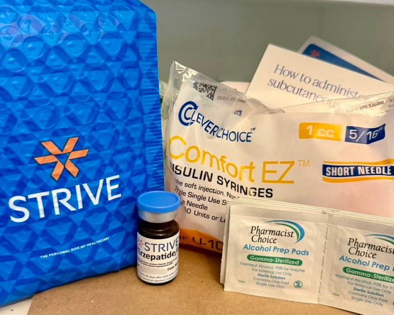 Blue Strive mailer with the personal side of healthcare tagline and the amber tirzepatide vial in front / Blue Strive mailer, tirzepatide vial, Clever Choice syringes, alcohol pads, and the injection card arranged together