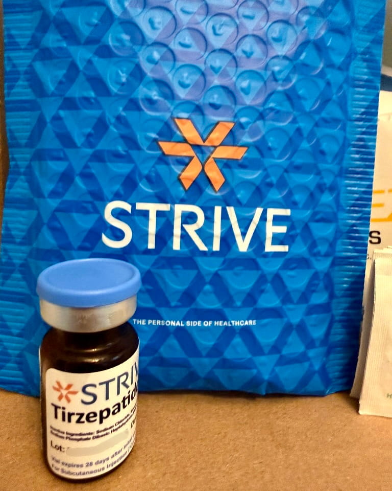 Blue Strive Pharmacy bubble mailer with a prescription vial in front of it.