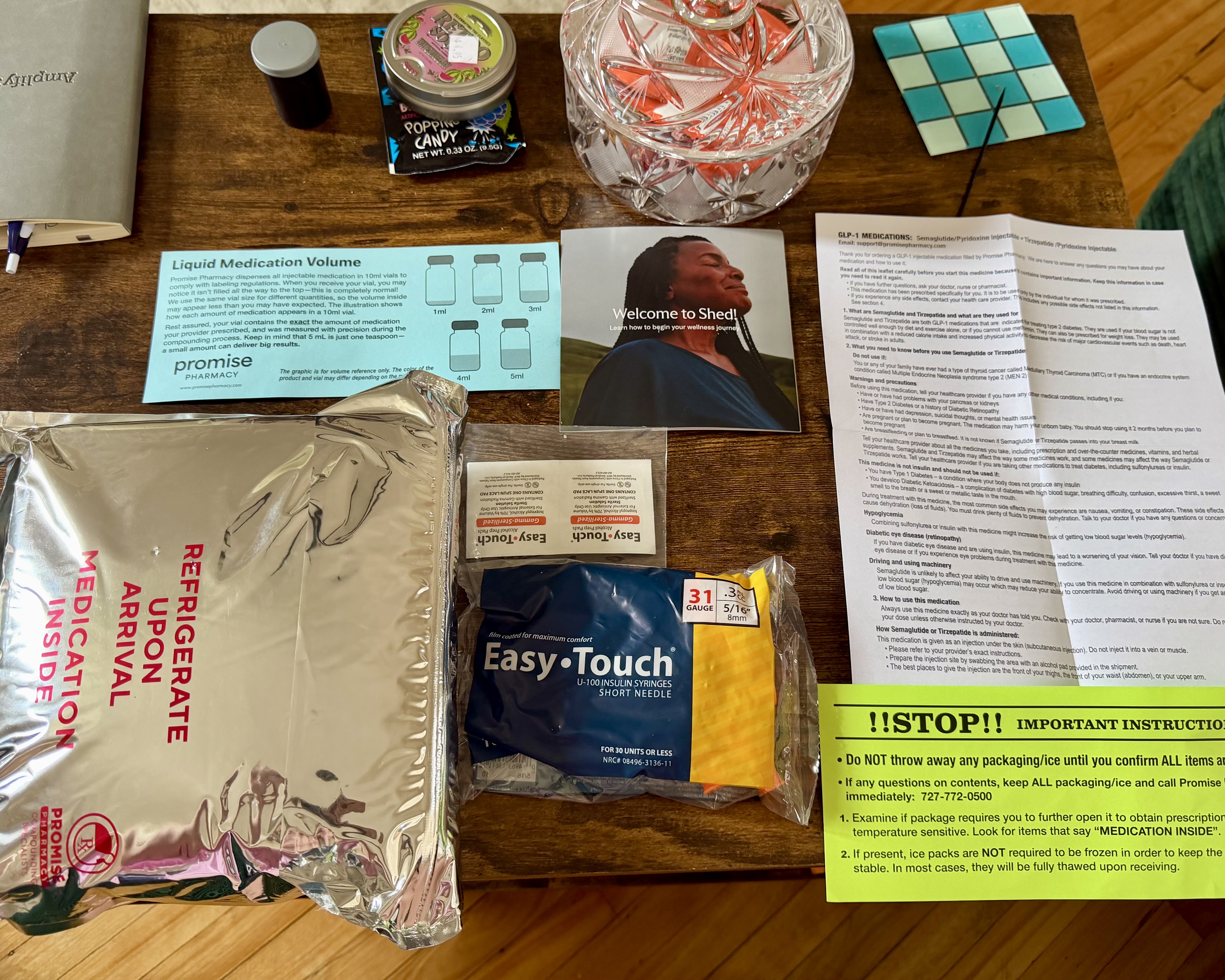 Everything from the Shed mailer laid out: mylar pouch, syringes, alcohol pads, volume card, welcome card, and GLP-1 leaflet