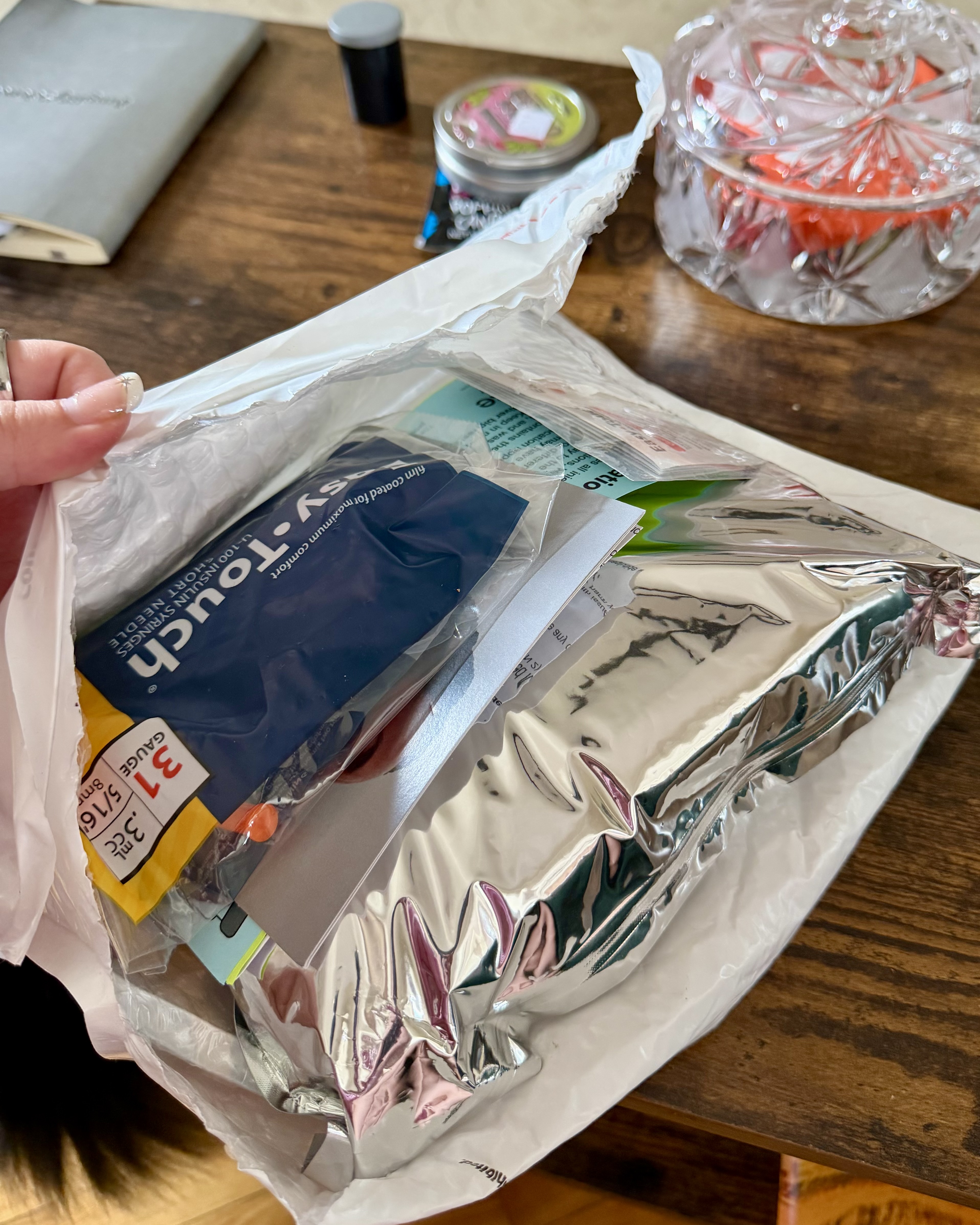 Opened Shed mailer showing a sealed silver mylar pouch and Easy Touch insulin syringes inside