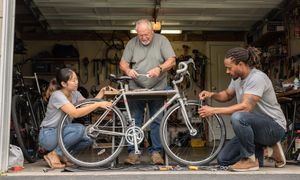 two-people-fixing-bike-in-garage-with-man.jpg