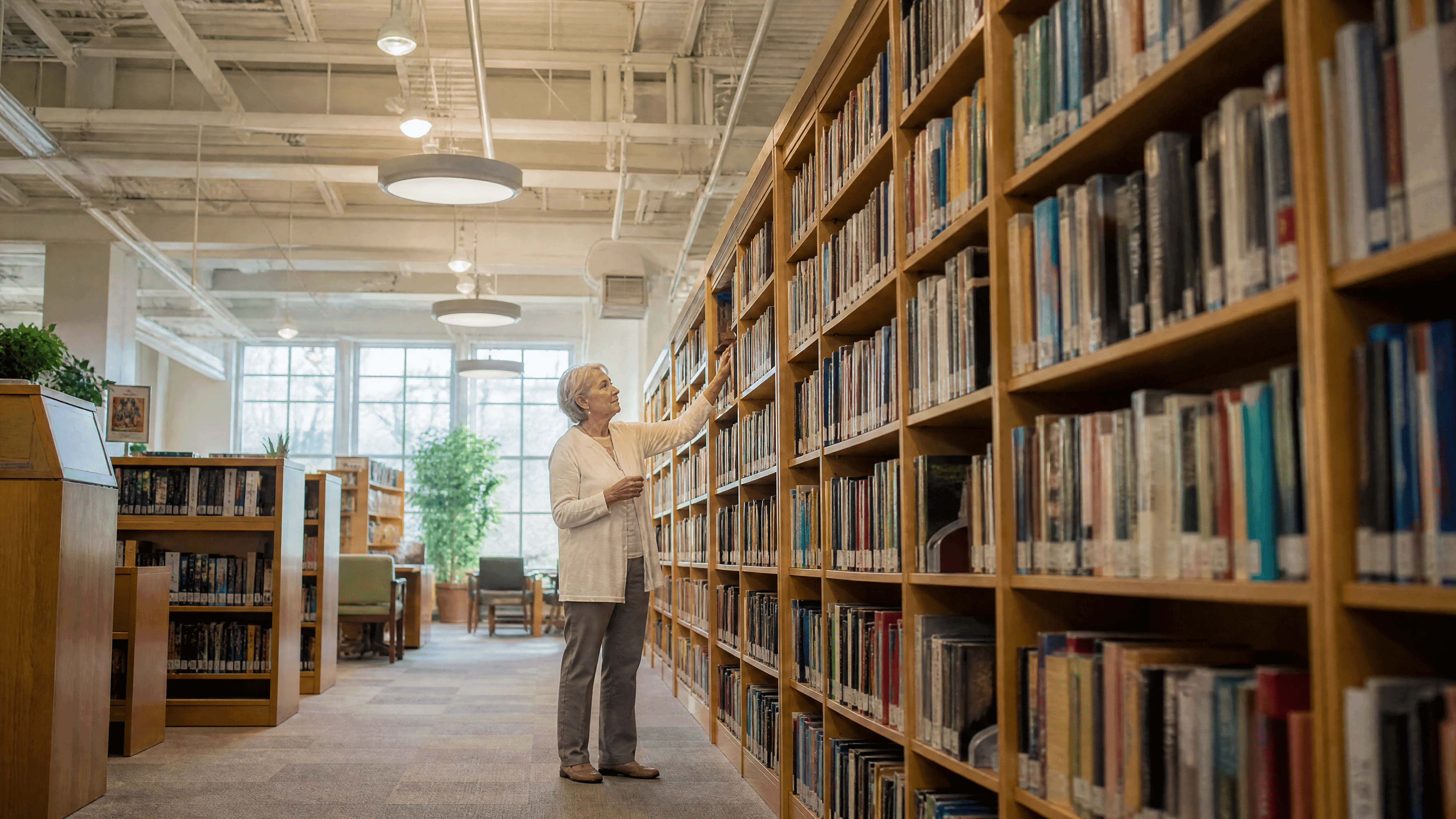 woman in her 60s reaching for a book in the library