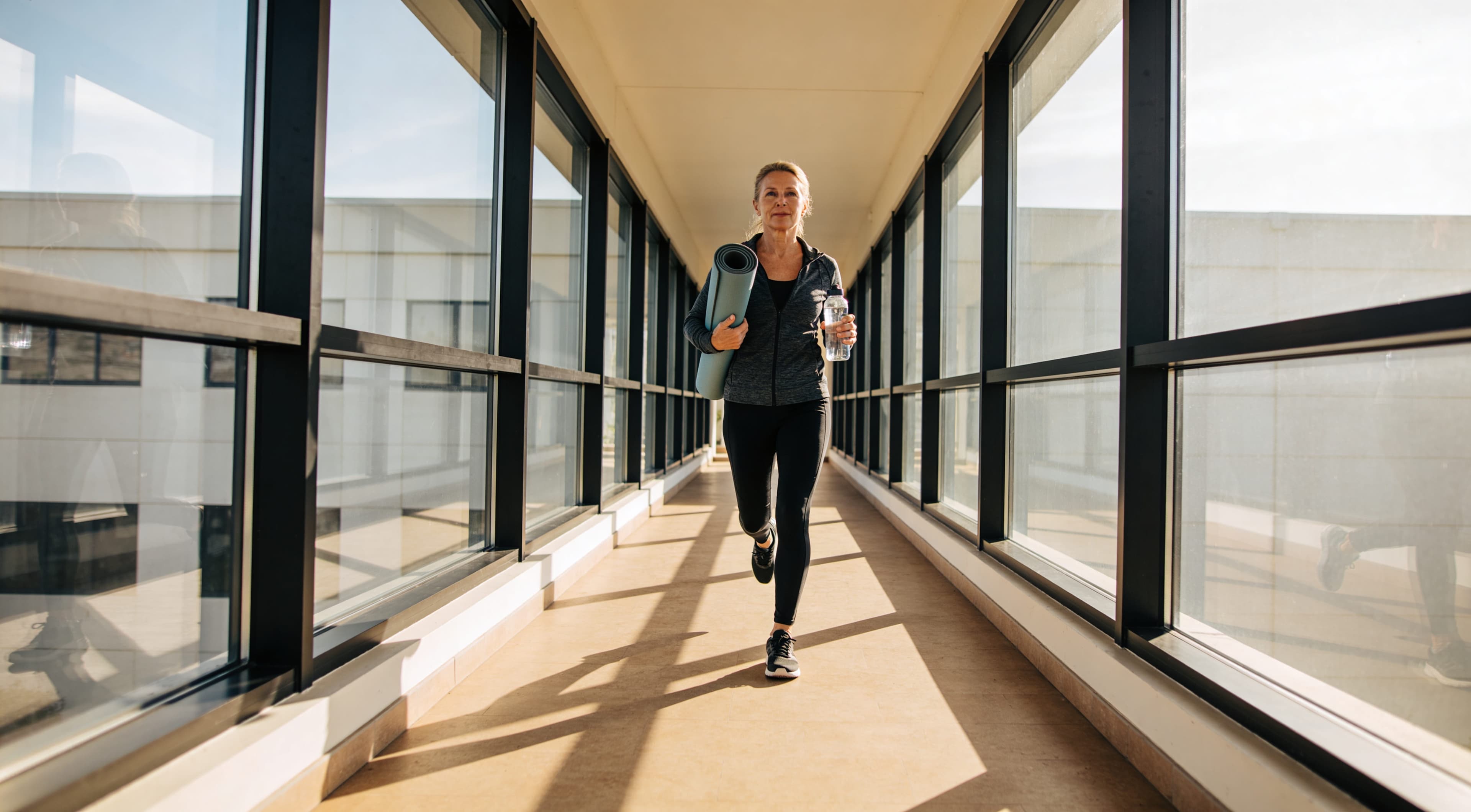 woman-walking-with-yoga-mat-in-hallway.jpg